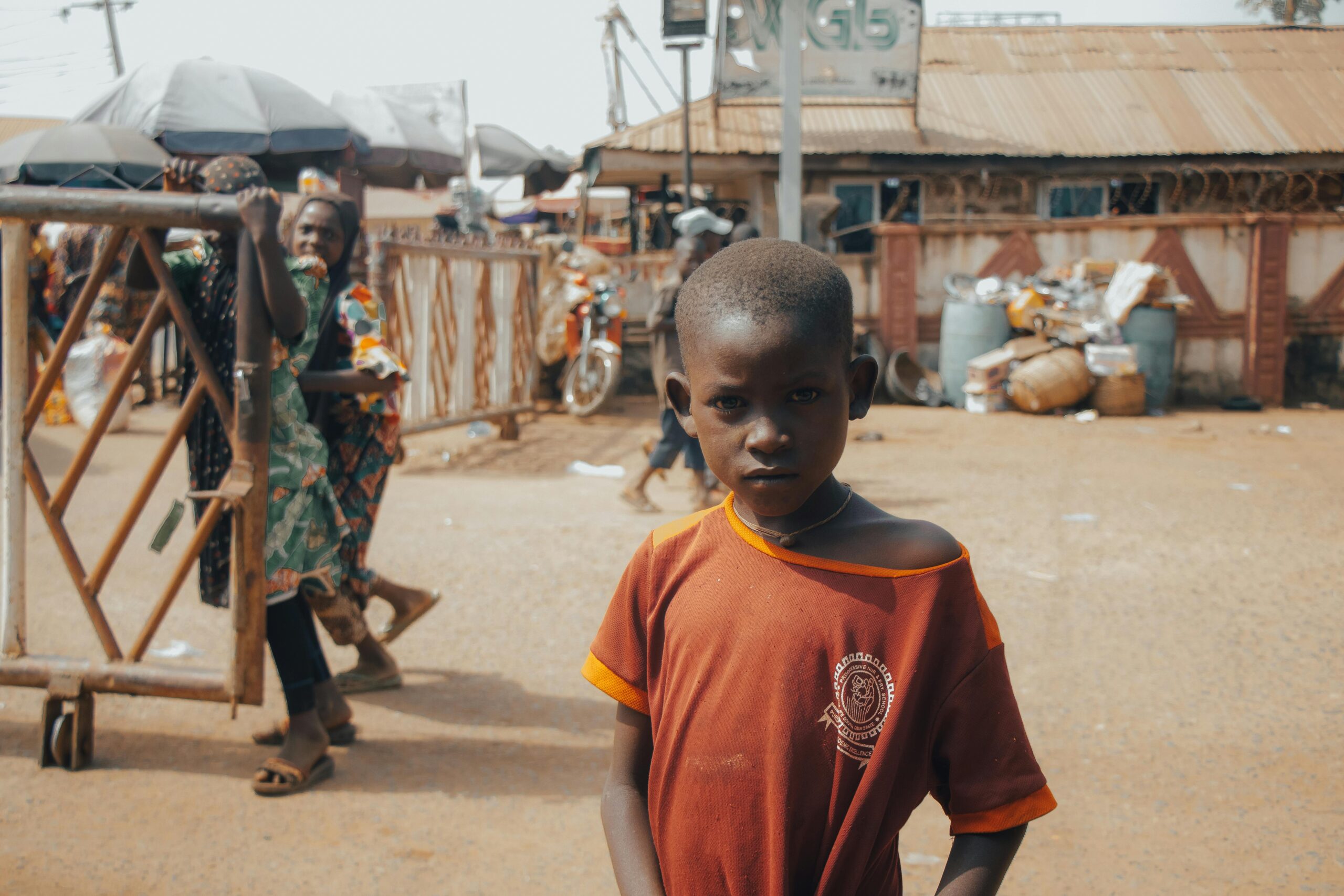 Portrait of a young boy in a bustling village market, reflecting daily life and culture.